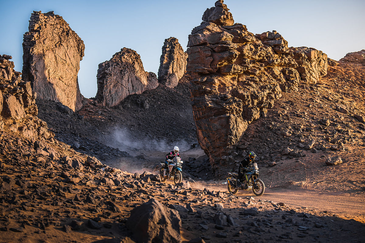 Two CFMOTO 450MT in Tundra Grey and Zephyr Blue riding between two rocks in desert environment